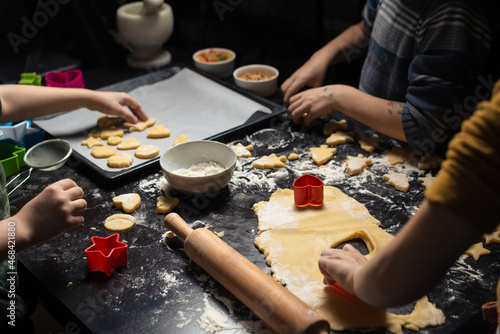 Children cook New Year's cookies together. Carving Christmas trees and stars out of dough. Preparation for the holiday. Homemade sweets.