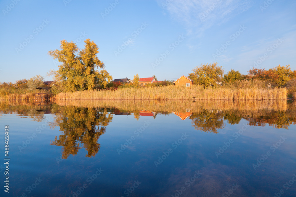 Beautiful autumn landscape perfectly reflected in the river on a sunny day.