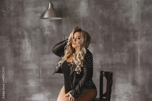 Plus-size woman with long blond hair in a leather jacket, overweight blonde with lush forms in the loft, full girl in black clothes with bright makeup