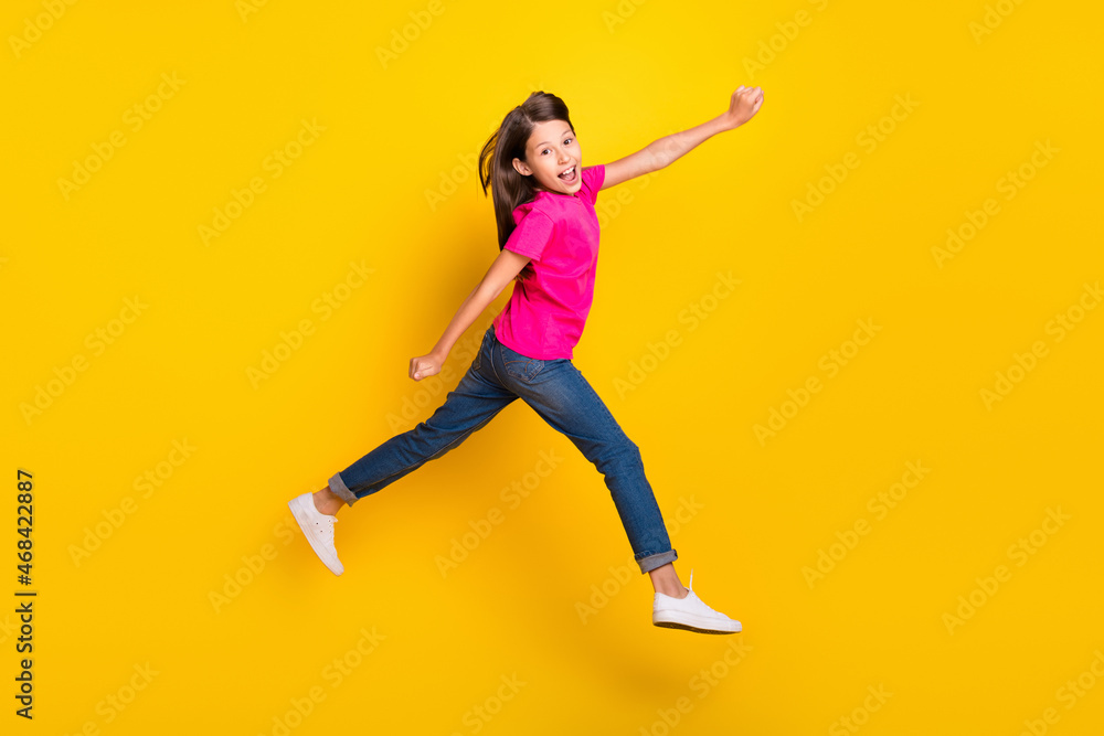 Photo of funky hurry sporty girl jump run fast rush side wear pink t-shirt jeans shoes isolated yellow color background