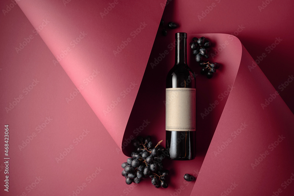 Bottle of red wine and blue grapes. - obrazy, fototapety, plakaty 