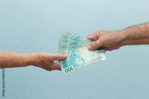 Mãos de idosos com dinheiro. Conceito de pagamento/recebimento. Uma pessoa entregando dinheiro para outra pessoa. photo