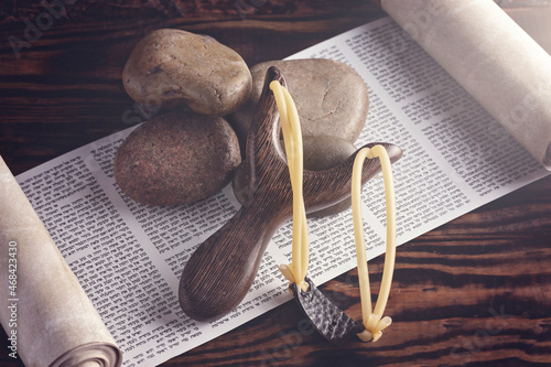 Five Smooth Stones and Sling Shot on a Hebrew Scroll Symbolising the Story of David and Goliath .