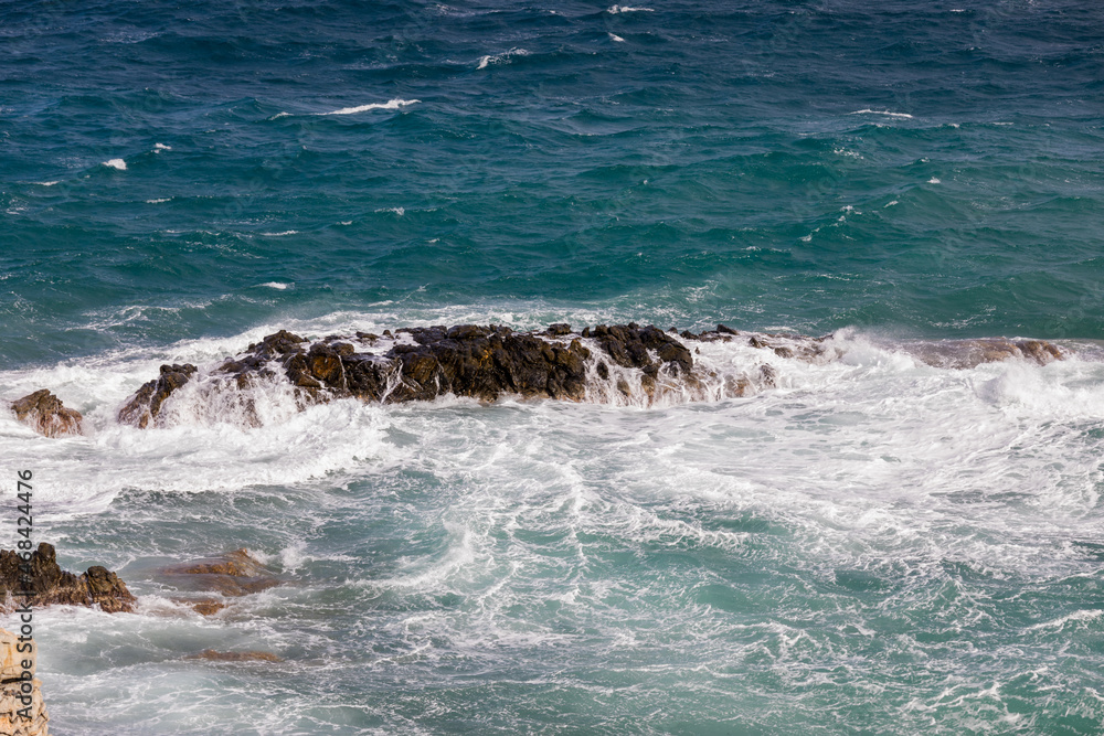 Obraz premium Rocks. White frothy waves hitting a rock by the seashore. Stock Image.