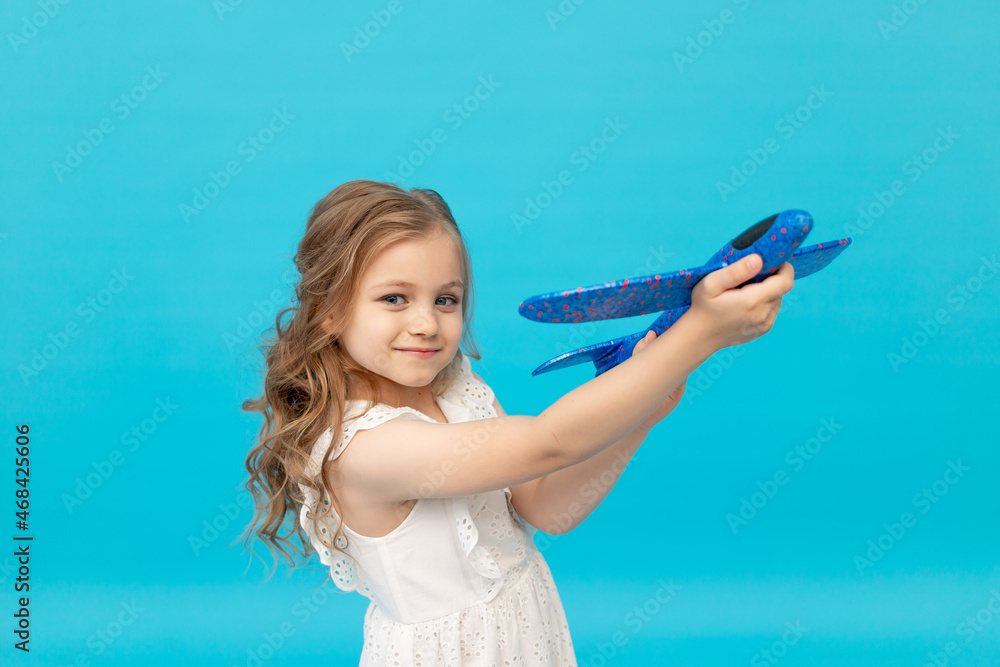 cute happy little girl in a cotton white dress on a blue background ...