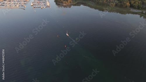 Aerial view of a boat arriving at a small marina outside Gothenburg on a beautiful summer evening at sunset. 4K drone footage.