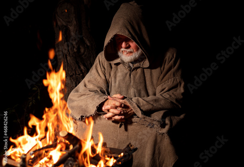 Medieval man sitting by the fire at night and pray