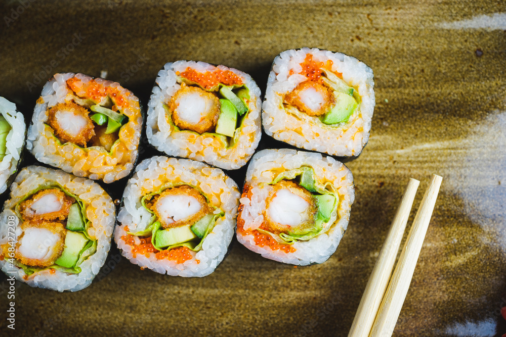 Traditional Japanese rolls with shrimps and vegetables on a plate with wooden chopsticks Traditional Japanese rolls with shrimps and vegetables on a plate with wooden chopsticks