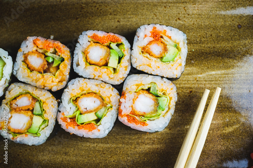Traditional Japanese rolls with shrimps and vegetables on a plate with wooden chopsticks