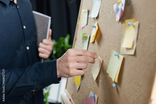 Cropped view of programmer pinning sticky notes on board © LIGHTFIELD STUDIOS