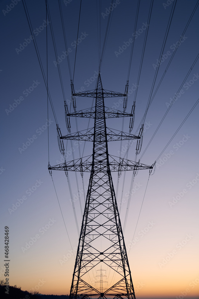 Electricity pylon (Strommasten) also overhead line pylon as a silhouette. In Winter at sunset. Up view.