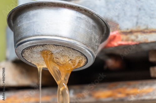Demonstration of how to use an old fashioned cast iron apple press. Preparation of fresh apple juice with an old fruit press. Selective focus, apple juice flowing close up