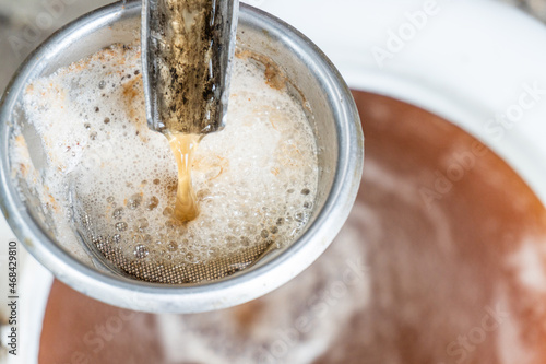 Demonstration of how to use an old fashioned cast iron apple press. Preparation of fresh apple juice with an old fruit press. Selective focus, apple juice flowing close up