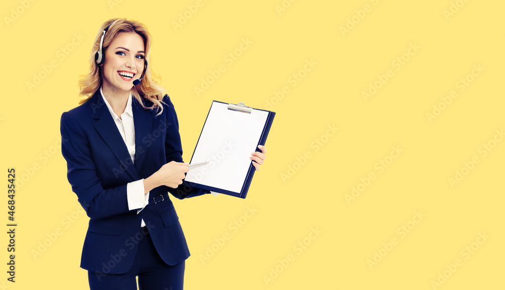 Call center. Businesswoman or female support phone operator in headset, showing blank clipboard with copy space for text, yellow background. Customer service help line consulting concept. Call center. Businesswoman or female support phone operator in headset, showing blank clipboard with copy space for text, yellow background. Customer service help line consulting concept.
