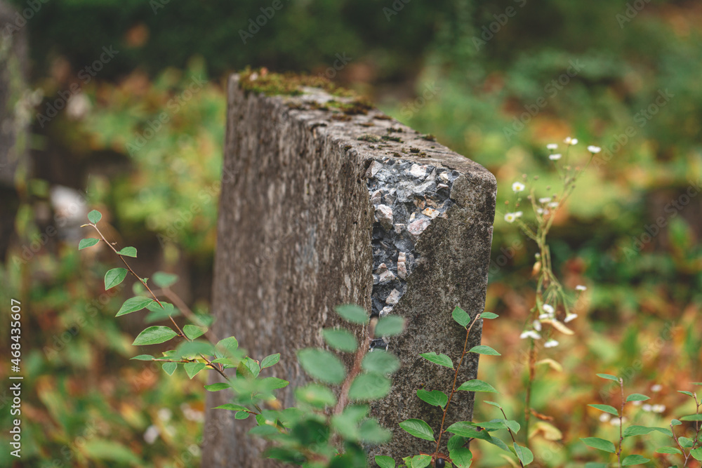 A broken gray cement grave stone in green grass of an old cemetery. A broken gray cement grave stone in green grass of an old cemetery.