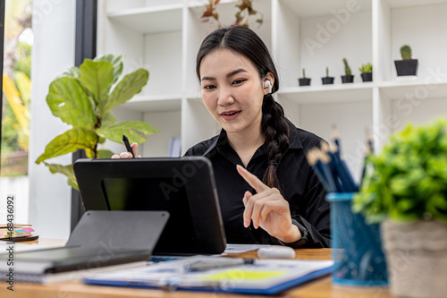 A beautiful Asian woman working in a private room, she is having a video conferencing with her supervisor and colleagues due to the company's work-from-home policy. The idea of working from home. © kamiphotos