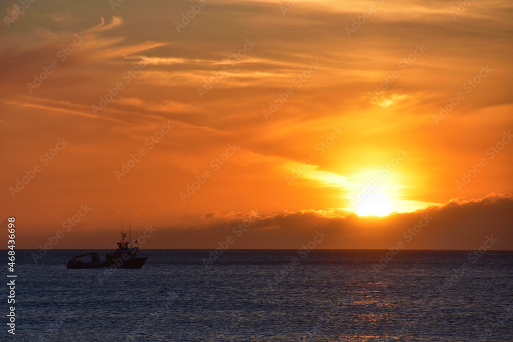 Sunset on the sea with clouds and a boat on the beach of Doniños de Ferrol