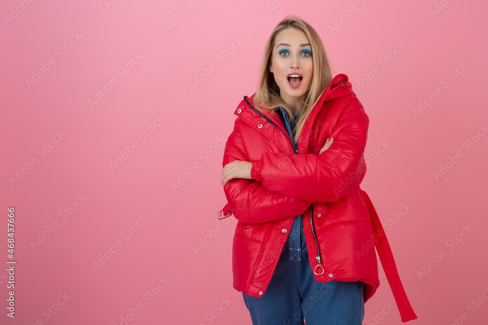blond happy attractive active woman posing on pink background in colorful winter down jacket of red color, having fun, warm coat fashion trend, smiling blond happy attractive active woman posing on pink background in colorful winter down jacket of red color, having fun, warm coat fashion trend, smiling