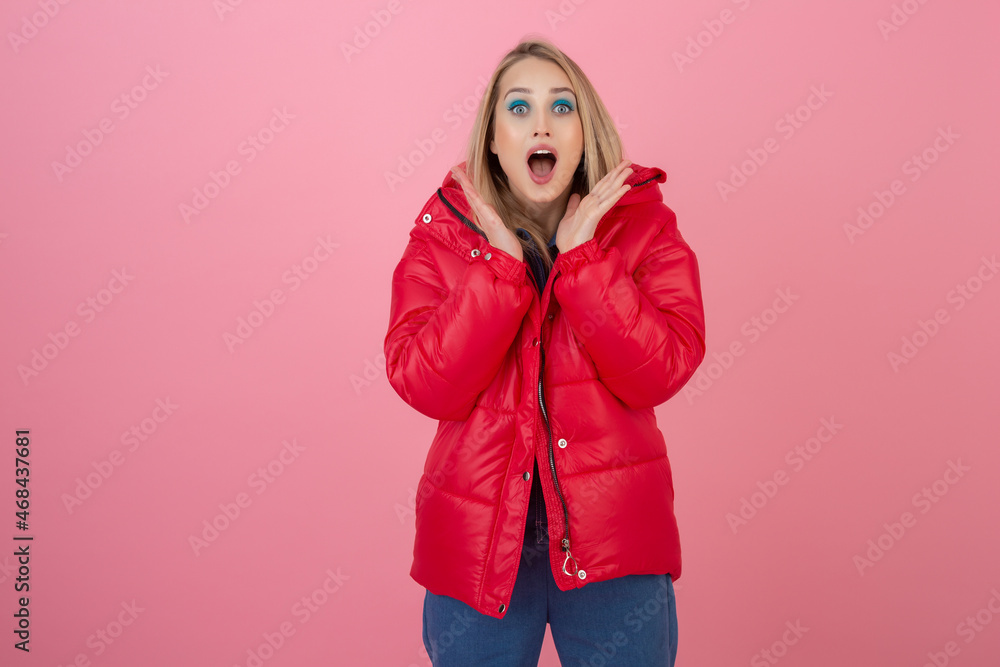 blond happy attractive active woman posing on pink background in colorful winter down jacket of red color, having fun, warm coat fashion trend, smiling blond happy attractive active woman posing on pink background in colorful winter down jacket of red color, having fun, warm coat fashion trend, smiling