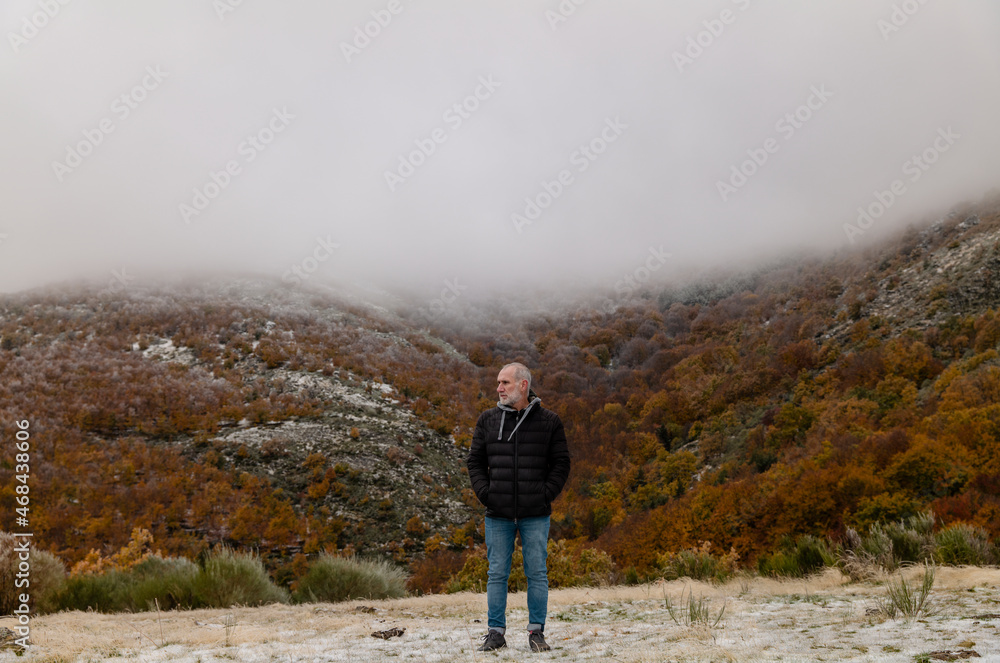 Portrait of adult man in black winter jacket against autumn color trees on mountain, in Tejera Negra, Cantalojas, Guadalajara, Spain
