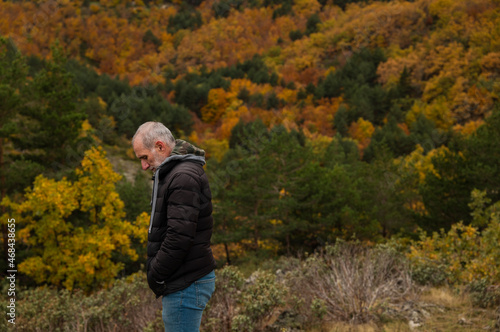 Portrait of adult man in black winter jacket against autumn color trees on mountain, in Tejera Negra, Cantalojas, Guadalajara, Spain