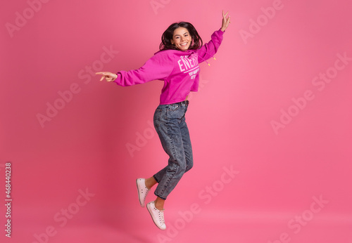 hispanic pretty woman in pink hoodie smiling jumping