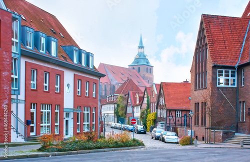 The sozy street in Luneburg with small residentian houses and St Michael church on background, Germany photo