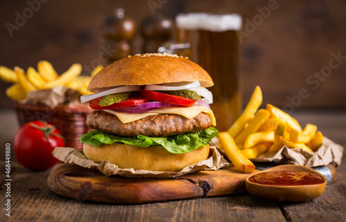 Hamburger with french fries and beer on wooden table