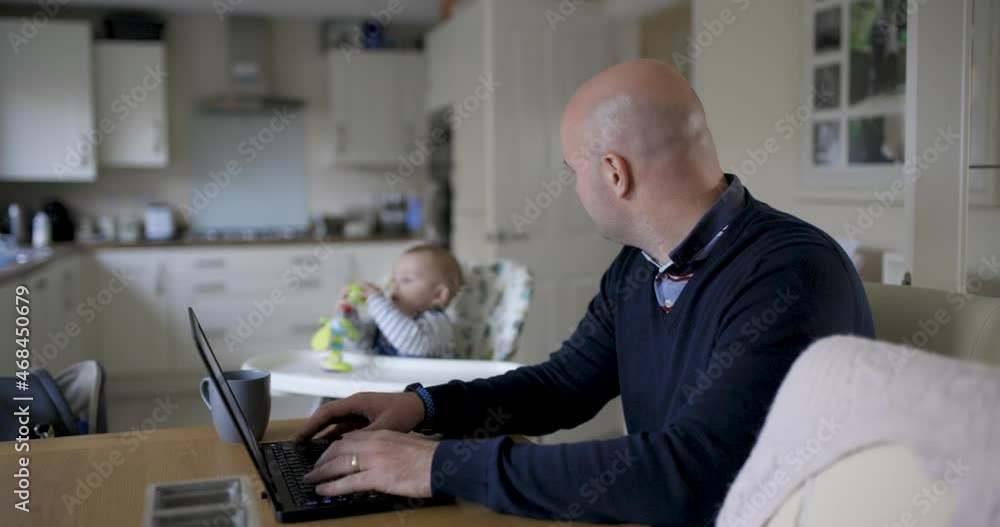 Young father working from home and playing with his newborn baby boy in the living room Young father working from home and playing with his newborn baby boy in the living room