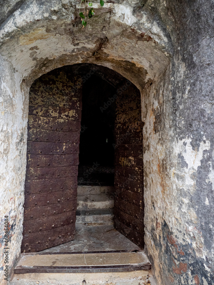 Heavy metal door opening to dark entrance and stone steps of old Spanish Spanjola Fortress.in Herceg Novi, Montenegro. 