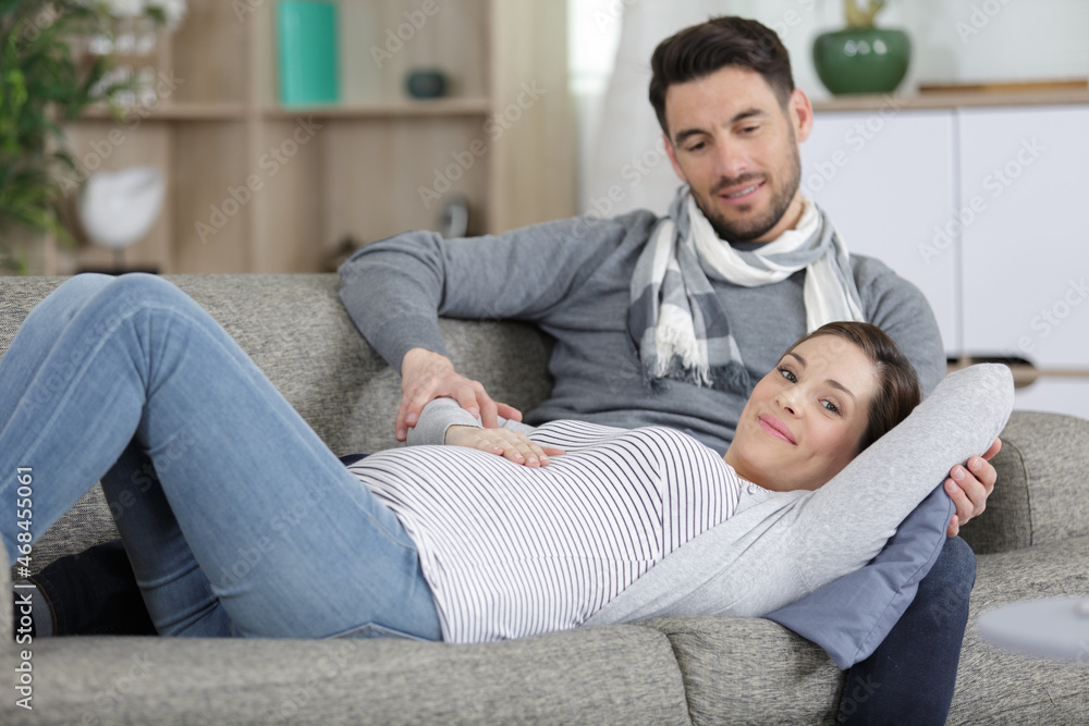 young man and pregnant woman lying on sofa young man and pregnant woman lying on sofa