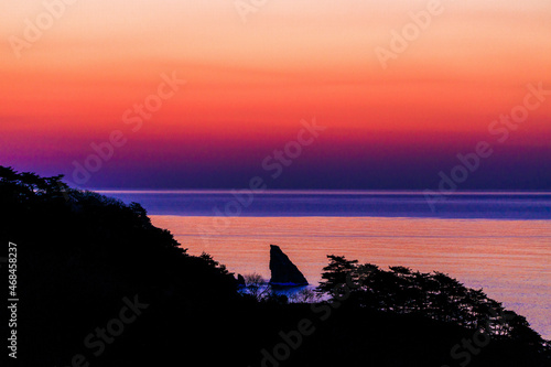 Far Eastern Marine Reserve. A sharp rock sticks out of the sea against the backdrop of a glow. Dawn in the Sea of Japan. Rocky coast in the south of the Far East.