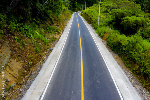 A hardened road divided with a yellow line running down a mountain slope