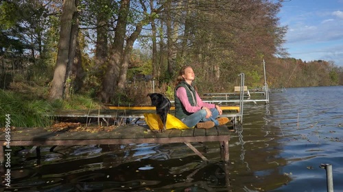 Frau mit ihrem Hund auf einem Steg am See