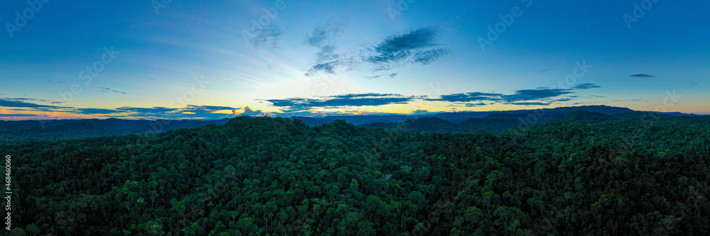 Panorama, silhoutte of mountains covered in trees with a beautiful late evening sunset