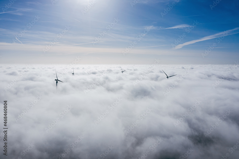 Wind farms sticking out above the clouds, aerial view of distant turbine propellers Wind farms sticking out above the clouds, aerial view of distant turbine propellers