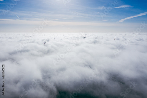 Wind farms sticking out above the clouds, aerial view of distant turbine propellers