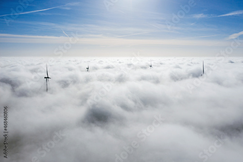 Wind farms sticking out above the clouds, aerial view of distant turbine propellers