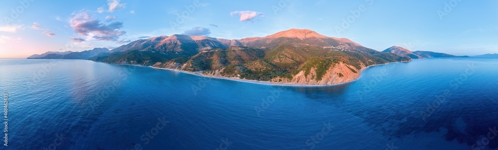 Aerial, panoramic view of a wild Mediterranean coast. Seascape, mountains and sea. Albania coast  Deep azure sea, warm colored rocks and mountains, blue sky. Saranda, Albania travel concept.