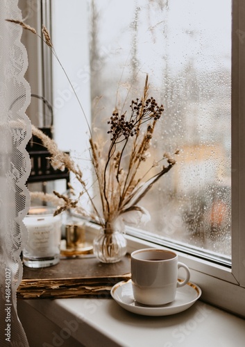 coffee cup and dry brown flowers on the window