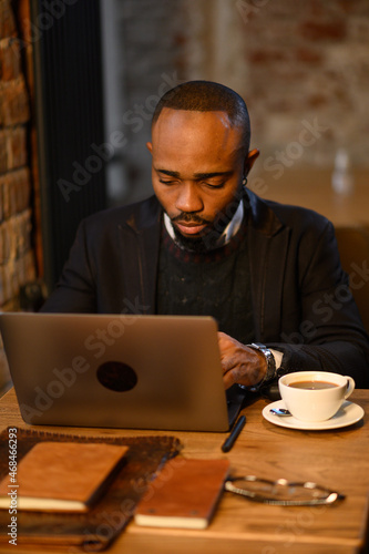 Confident young african man look at webcam conference video calling in office, happy mixed race entrepreneur talking doing online video chat job interview sit at desk