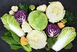 Fresh harvested vegetables from market on black background: white, red and savoy cabbage, broccoli and colorful cauliflower, napa cabbage and bok choy(pak choi)