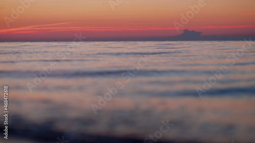 Sea horizon skyline at orange sunrise morning. Blue water waves splashing beach