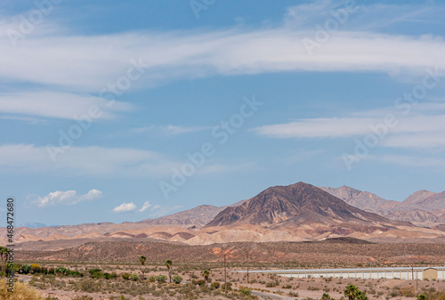 Lake Mead, Nevada, USA - May 22, 2011: Wide landscape with dry beige-red rocky shores and hills under blue cloudscape. Line of white public storage units cuts through it.