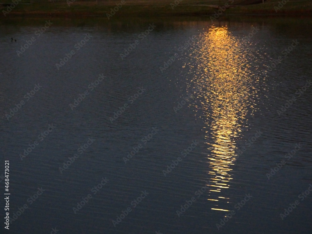 Wide shot of golden ripples in the water reflected from a full moon Wide shot of golden ripples in the water reflected from a full moon