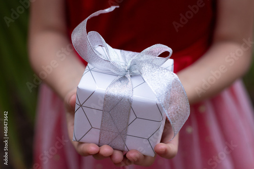 A close-up gift box lies in the hands of the child