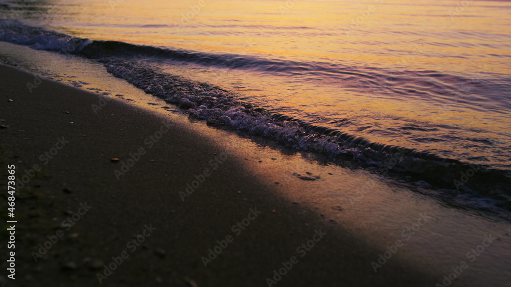 Closeup sea waves splashing sandy beach in cold evening sunset dusk slow motion