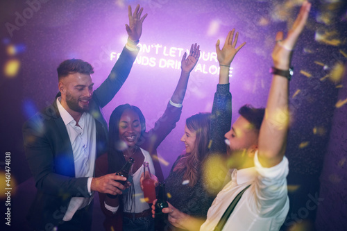 Happy group of friends dancing on a party in a club