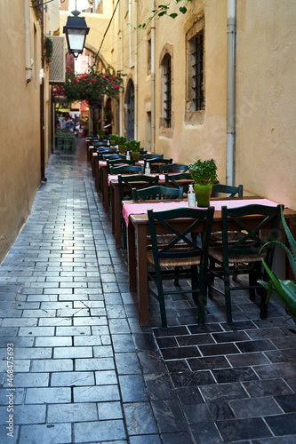 Restaurant chairs and tables set in a narrow street of the city of Chania on the island of Crete © GKor