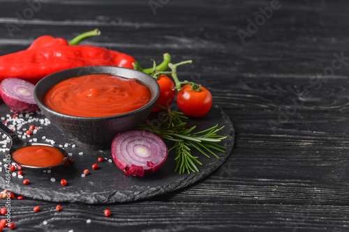 Bowl with organic tomato sauce on dark wooden background